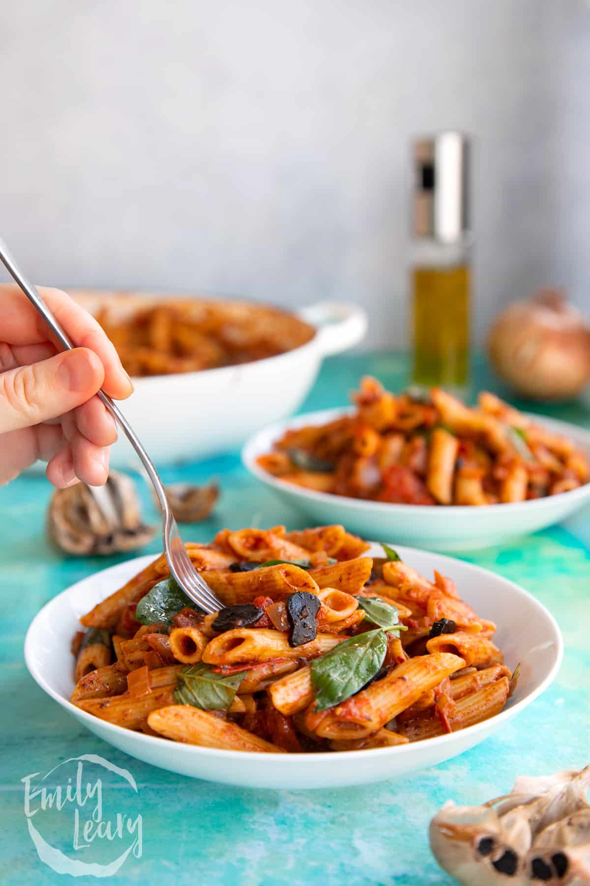 Side on shot of a bowl of black garlic pasta with a fork going in from the top.