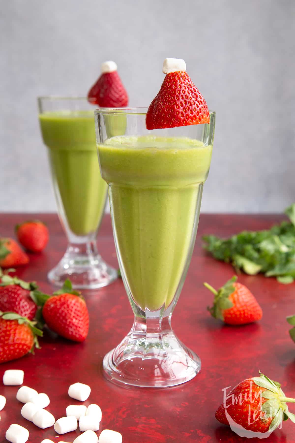 Side on shot of the finished grinch drink topped with santa hat strawberries.
