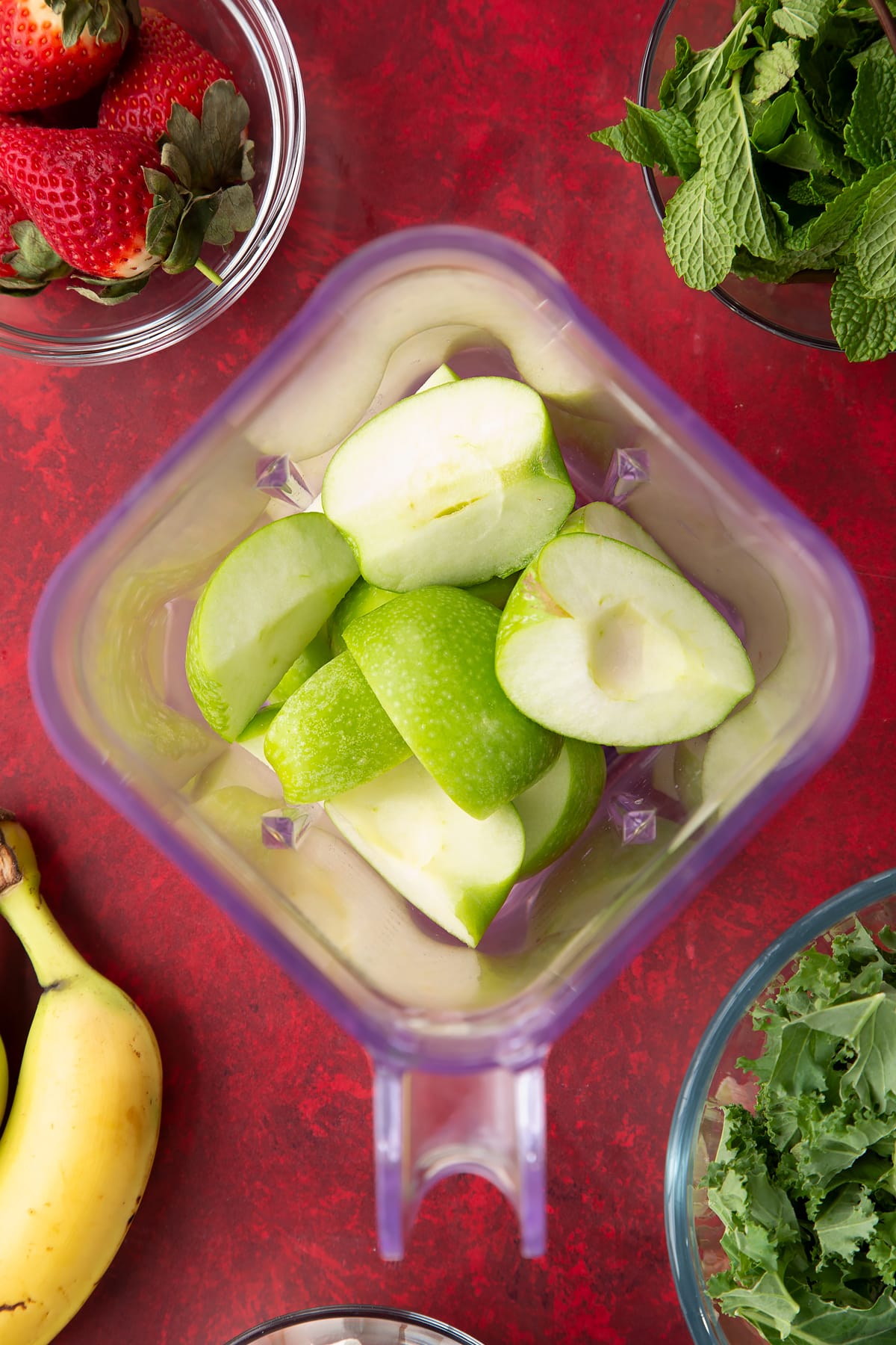 Overhead shot of sliced apples added to a blender.