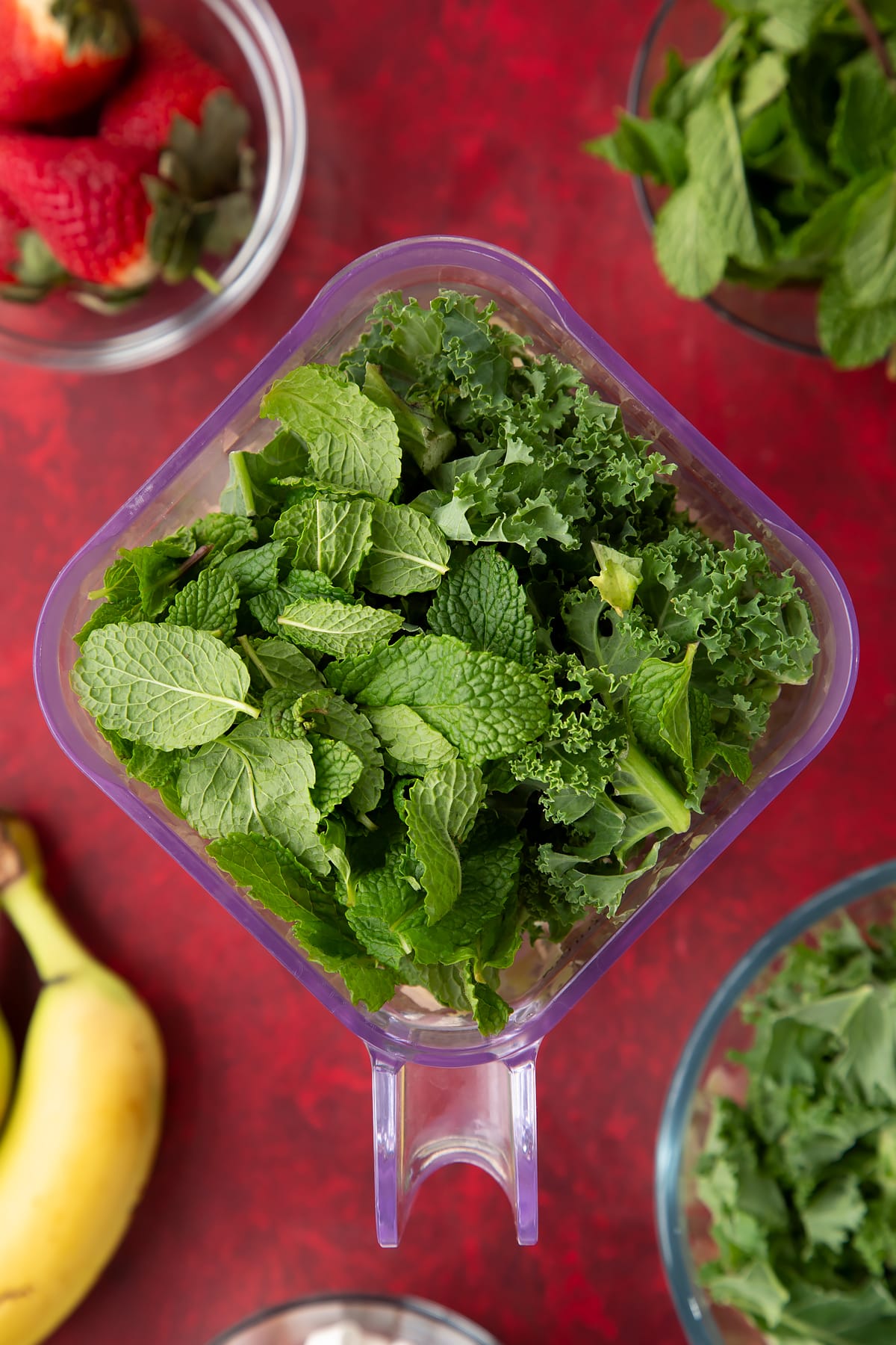 Overhead shot of kale and mint being added to the blender.