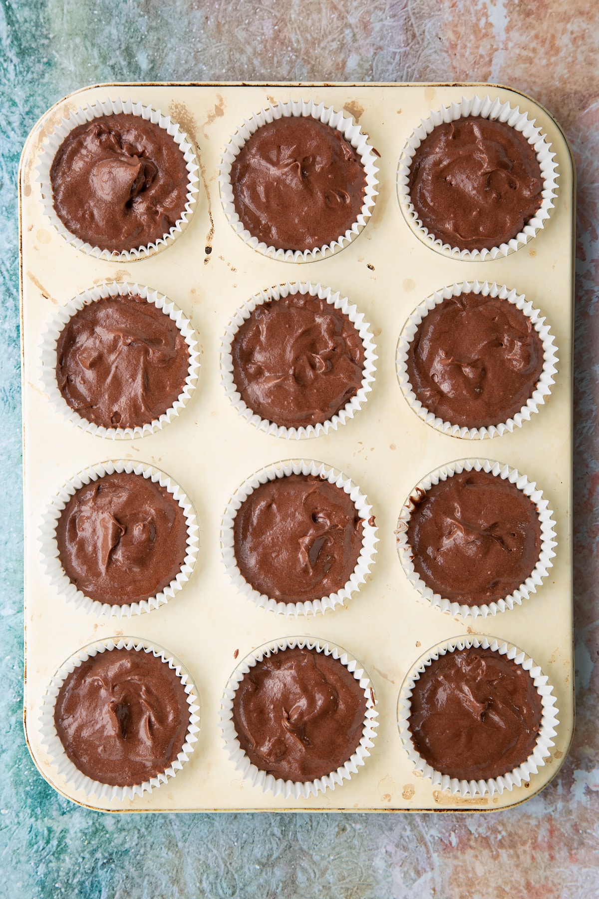 Overhead shot of the mint choc chip cupcakes mixture in cupcake cases in a cupcake tray.