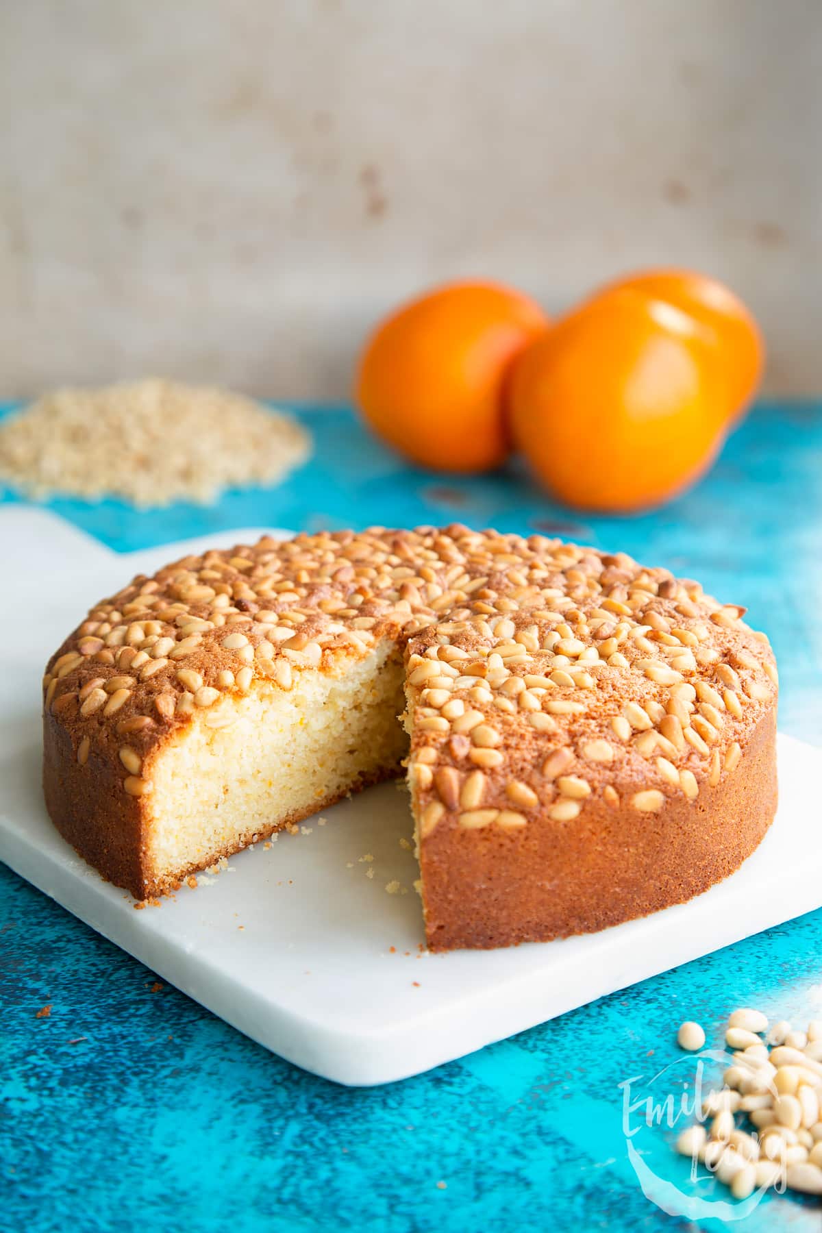 Pine nut cake on a white marble board with a slice taken out.