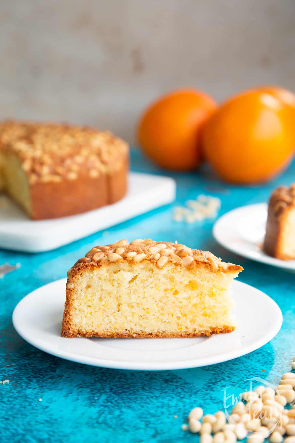 Slice of pine nut cake on a white plate. A fork rests on the plate.