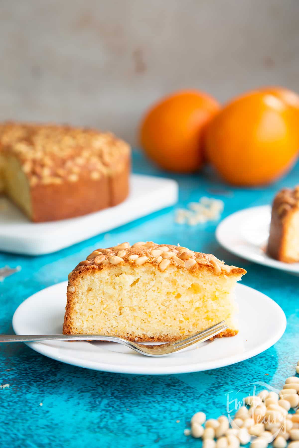 Slice of pine nut cake on a white plate. A fork rests on the plate.