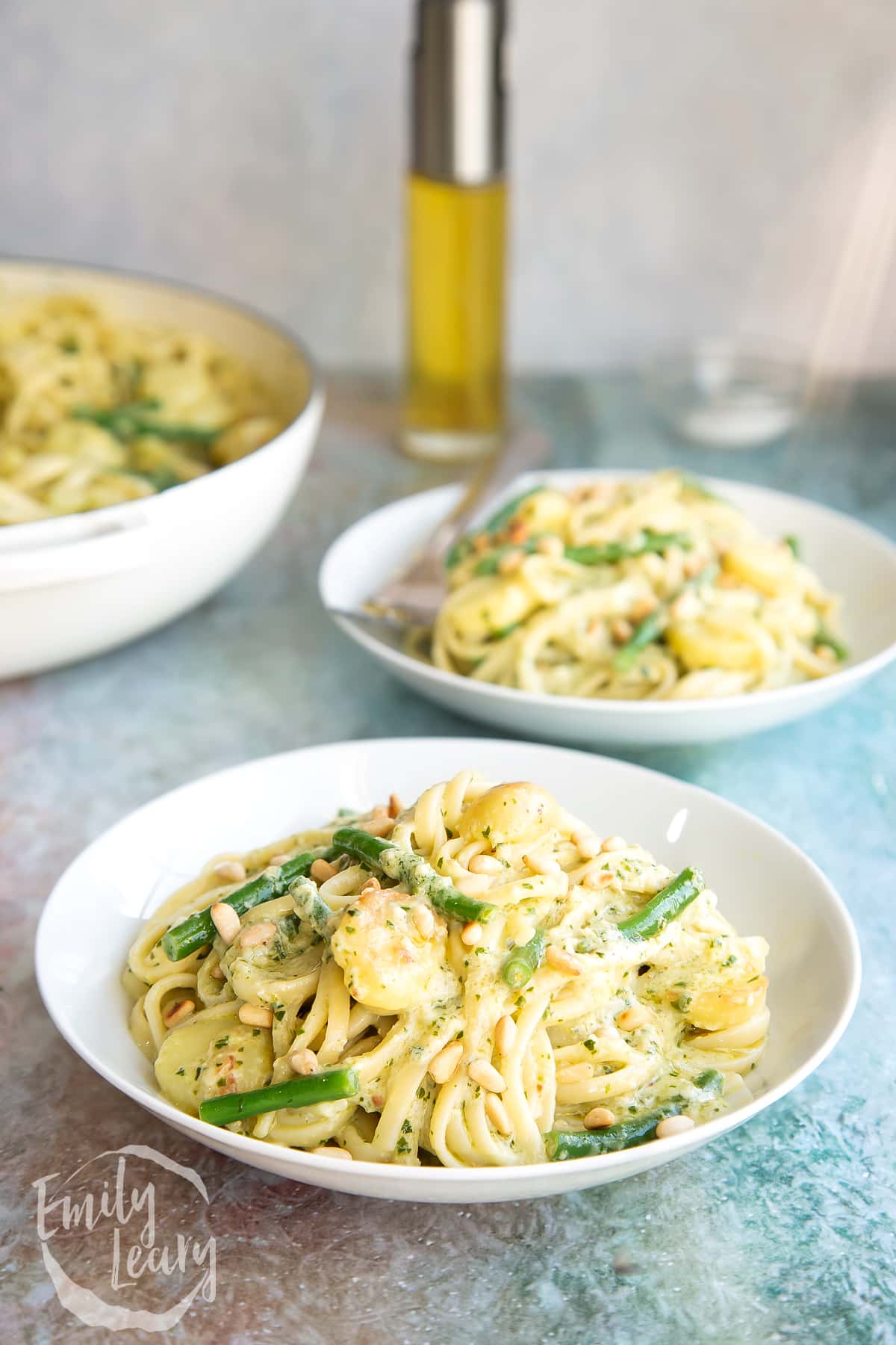 Close up shot of the finished Linguine alla genovese in a white bowl with additional servings in the background.