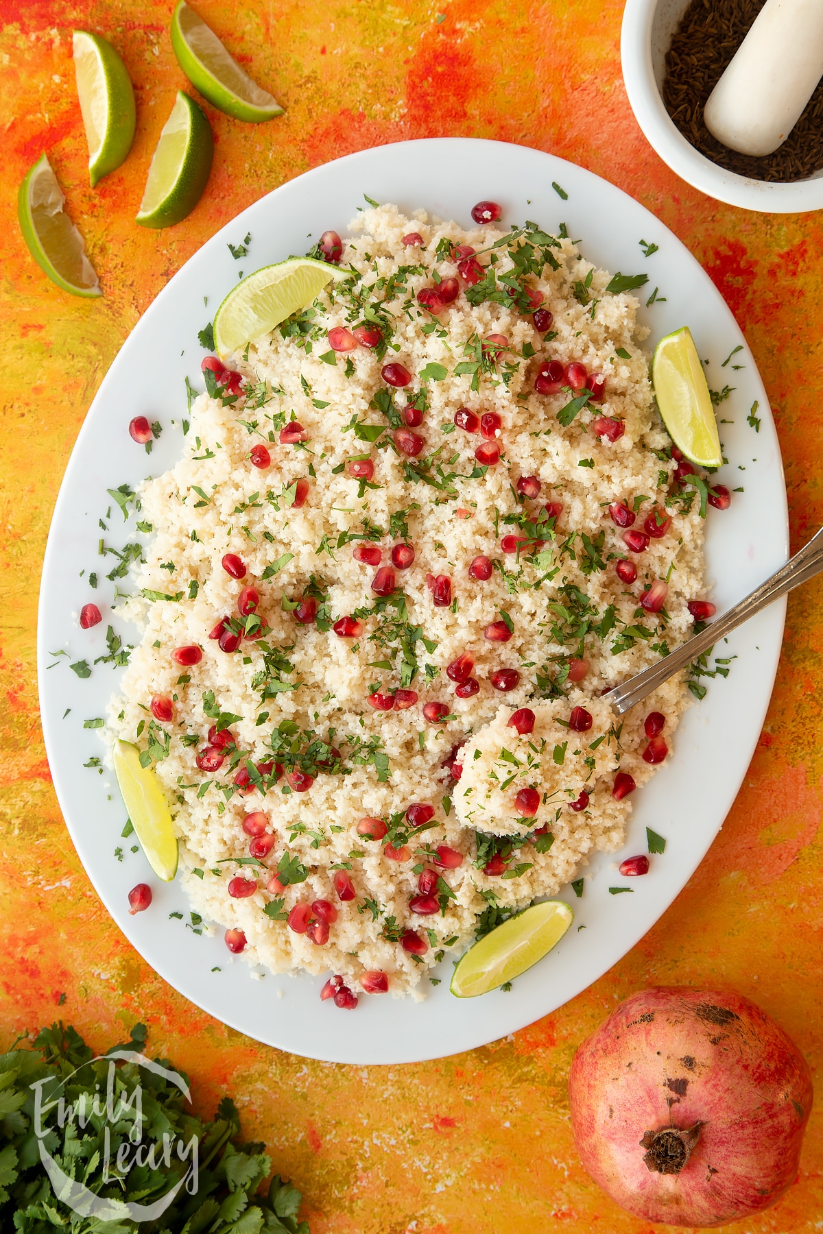 Overhead shot of the finished cauliflower couscous with pomegranate served on a white plate.