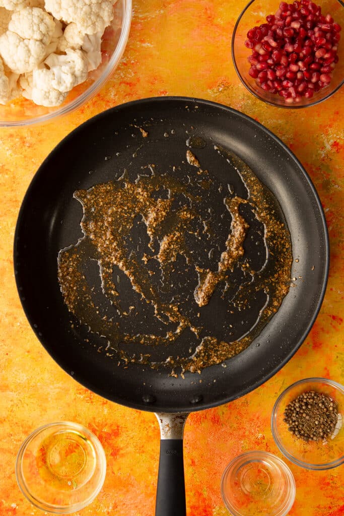 Overhead shot of the pan with oil and the cumin and coriander seeds having been on the hob for a couple of minutes.