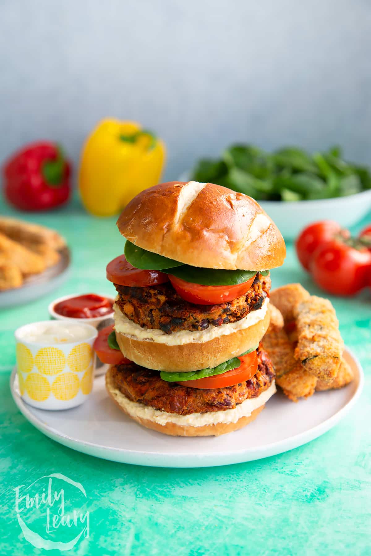 Double stacked kidney bean burger served on a white plate with dips on the side.