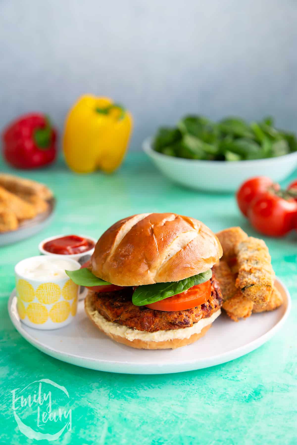 Finished kidney bean burgers served on a white plate with two dips on the side.