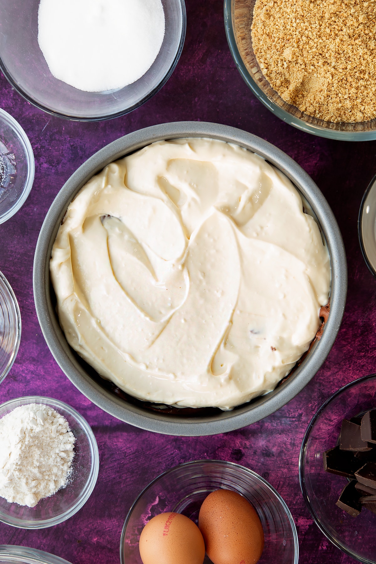 Adding the remaining vanilla cream cheese to the top of the non-stick cake tin to form the marble cheesecake.