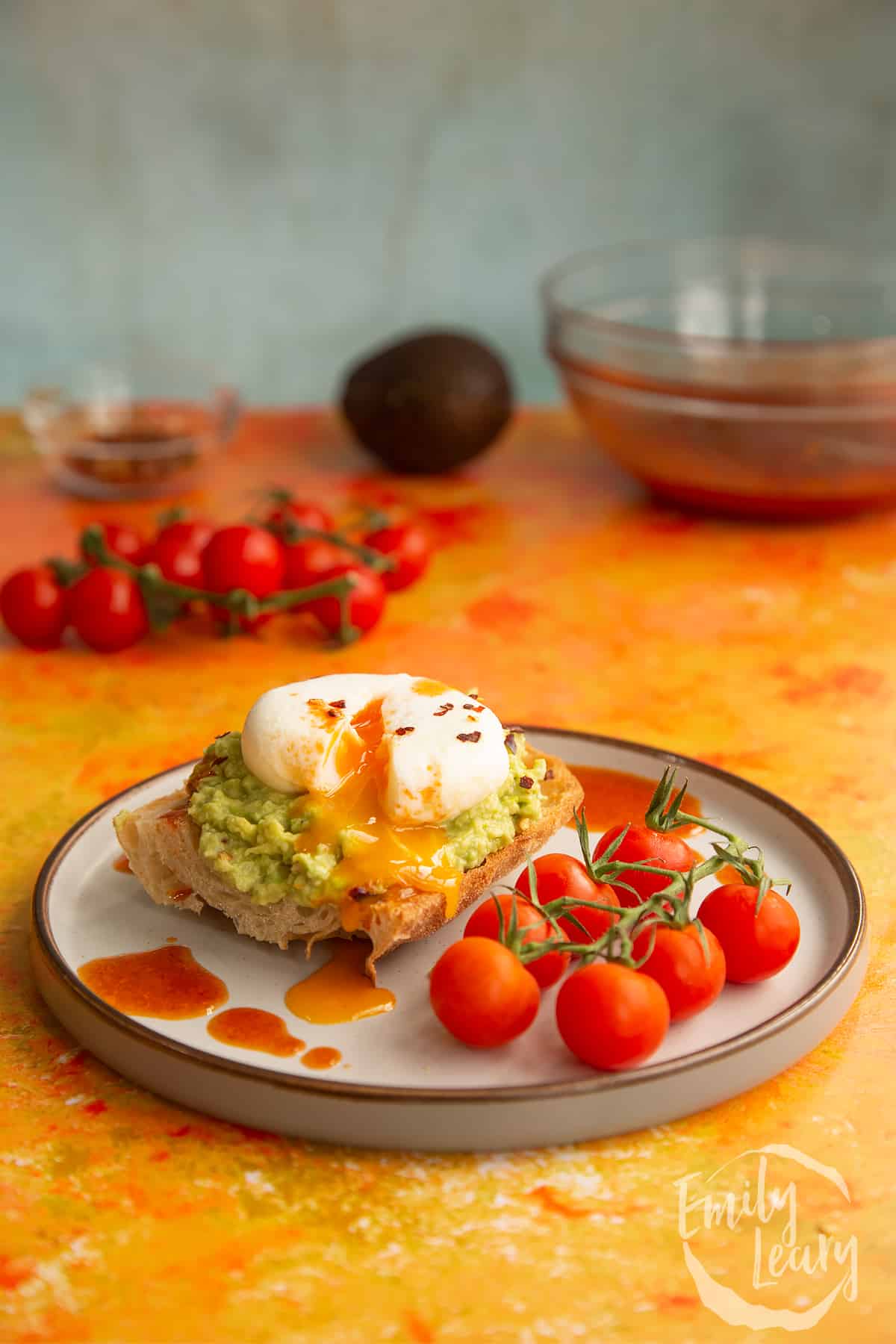 Side on shot of a plate of avocado and toast with a poached egg ontop.