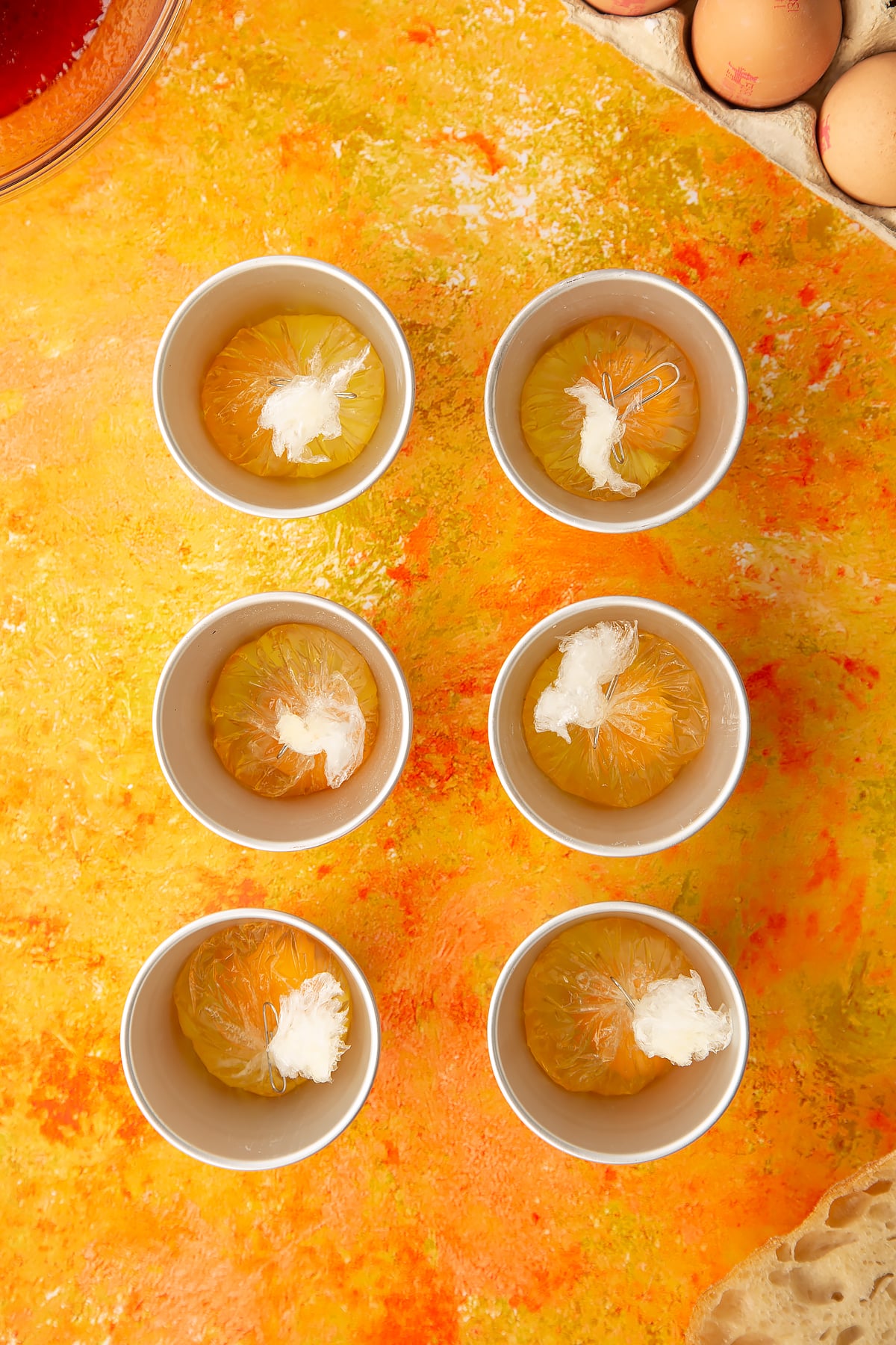 Overhead shot of the cracked eggs in clingfilm being clipped together.