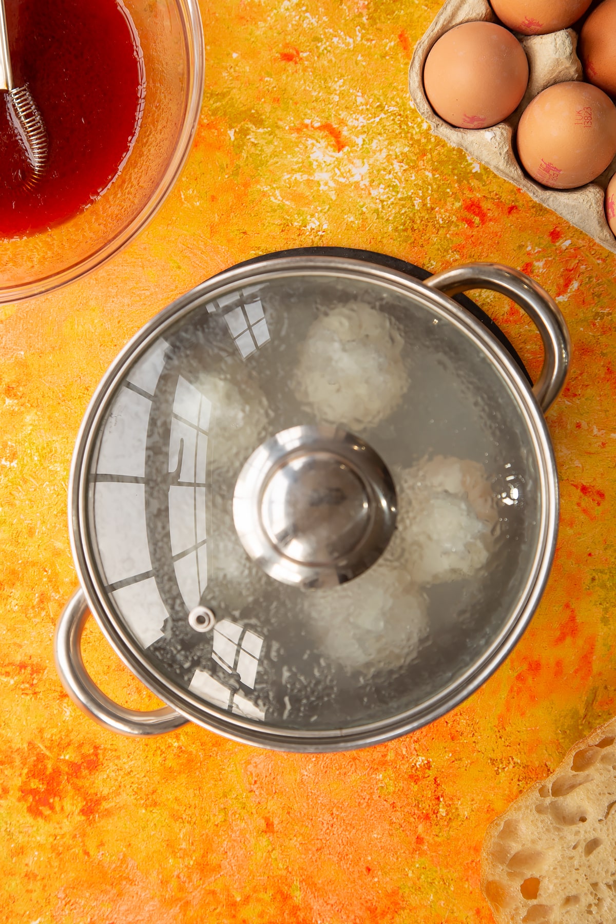 Overhead shot of a pan with the lid on and eggs inside clingfilm inside.