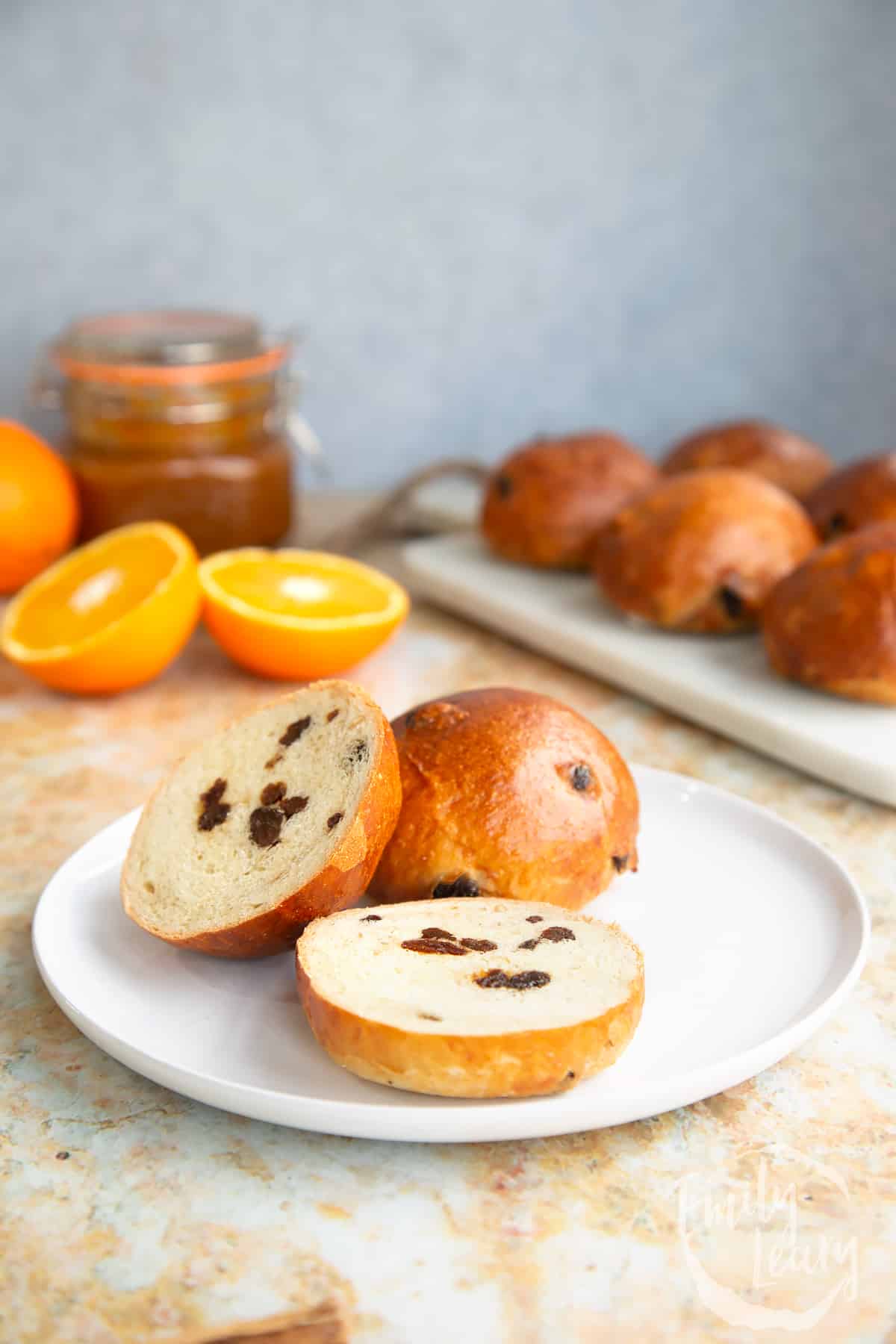 Sliced spiced fruit buns served on a white plate.