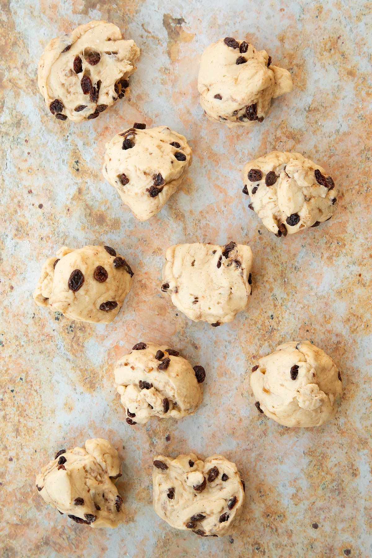 Overhead shot of the spiced fruit buns dough having been split into smaller balls.