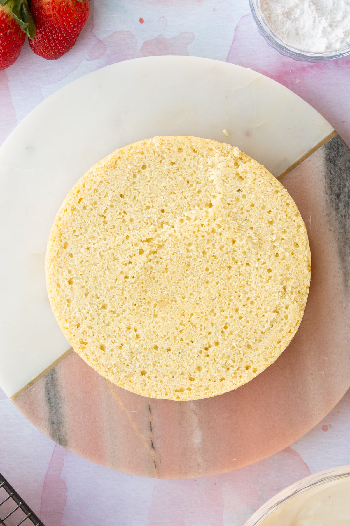 circular sponge cake on a pink marble board.