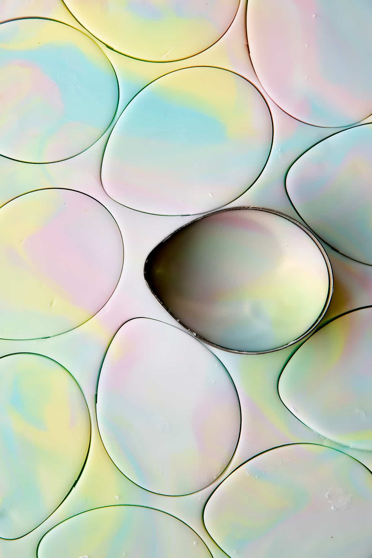 Overhead shot of an egg-shaped cookie cutter cutting out the icing.