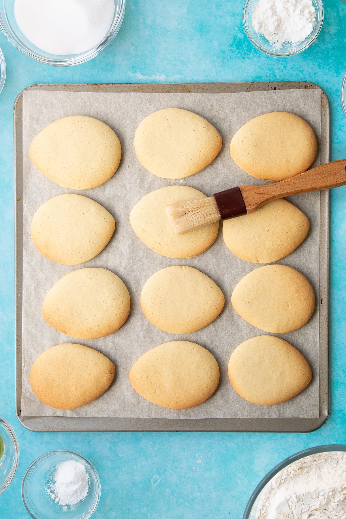 Overhead shot of a brush covering the eggs with icing sugar and water mixture.