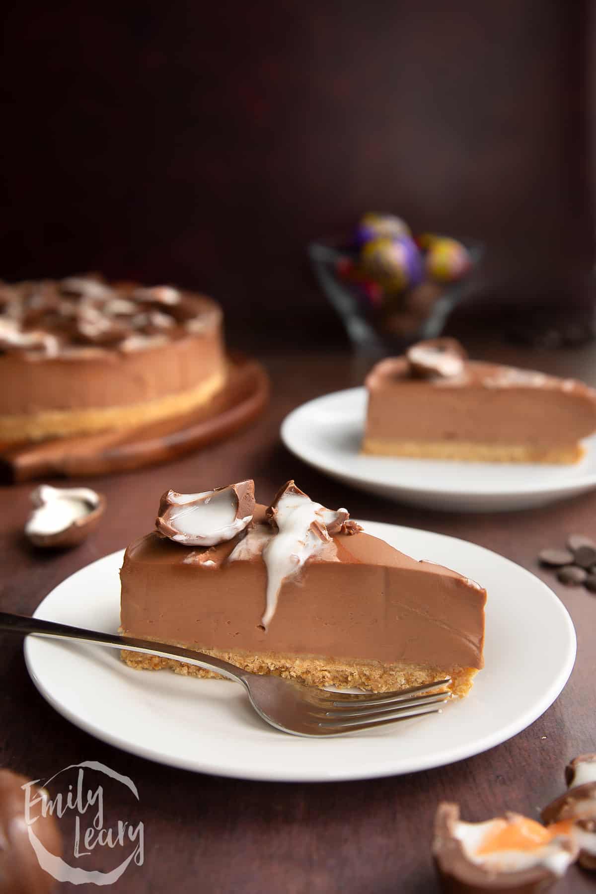 Finished slice of Cadbury Creme Egg cheesecake served on a white plate with a fork on the side.