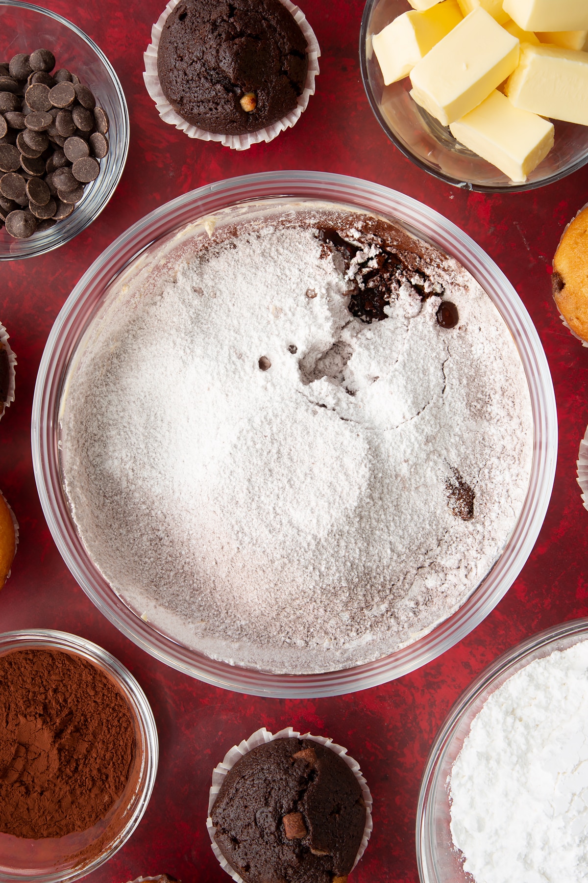 Adding icing sugar and cocoa powder, then add 1 tbsp of hot water and 1 tbsp vanilla to the bowl.