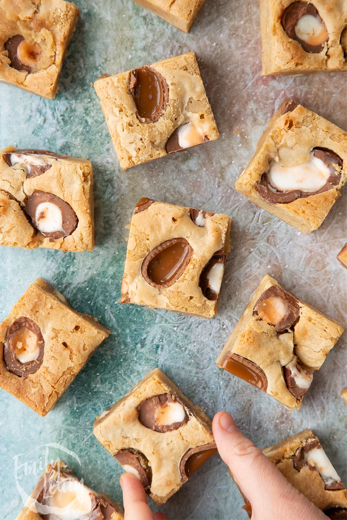 Hand reaching in to grab one of the finished easter blondies.