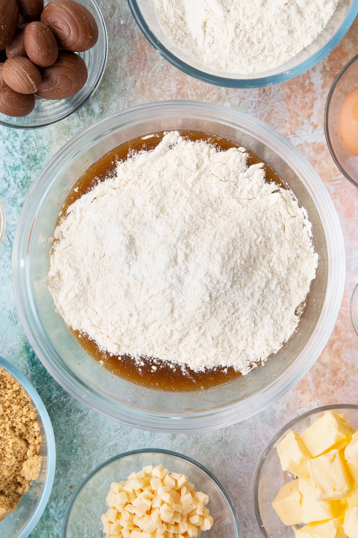 Adding flour and baking powder to the mixing bowl of easter blondies ingredients.