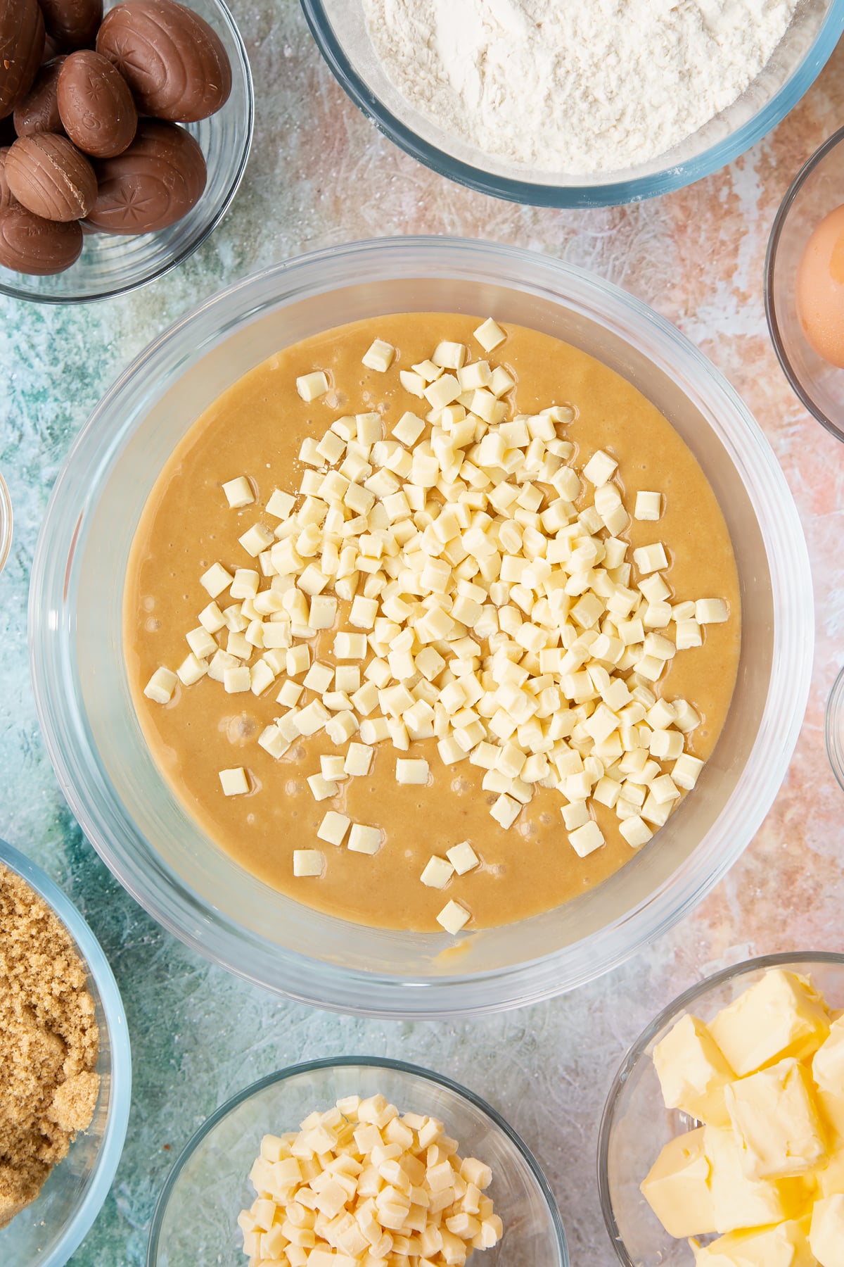 Adding white chocolate chips to the mixing bowl of wet easter blondies ingredients.