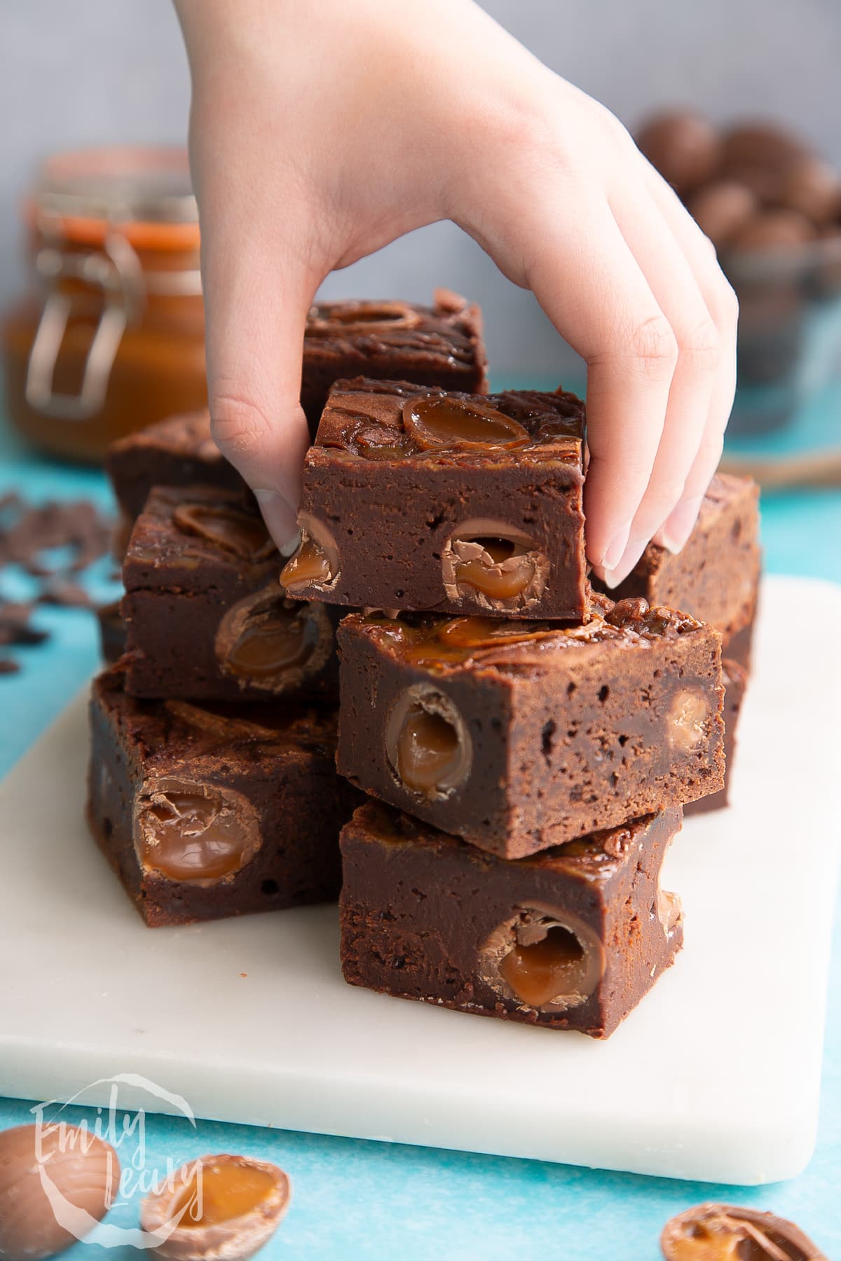 A hand reaching in to grab one of the finished easter brownies from the stack.