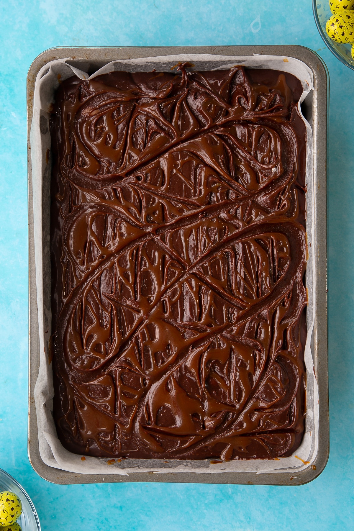 Overhead shot of the top caramel layer being swirled into the easter brownies mixture.