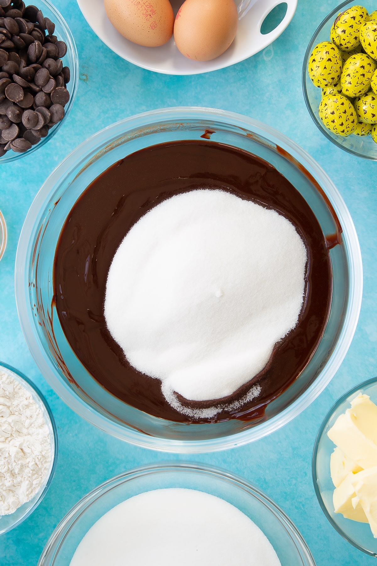Adding sugar to the wet mixture for the easter brownies in a mixing bowl.