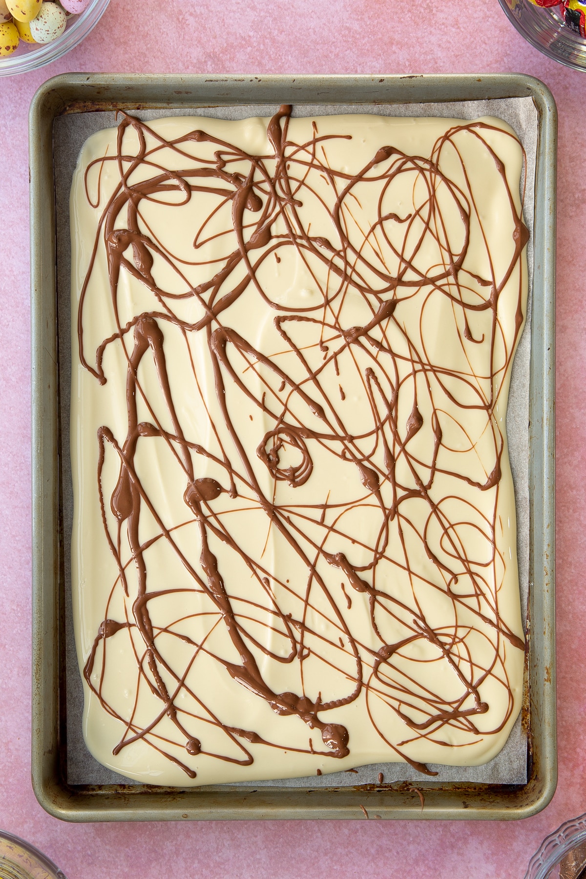 Drizzling milk chocolate over the top of the white chocolate.