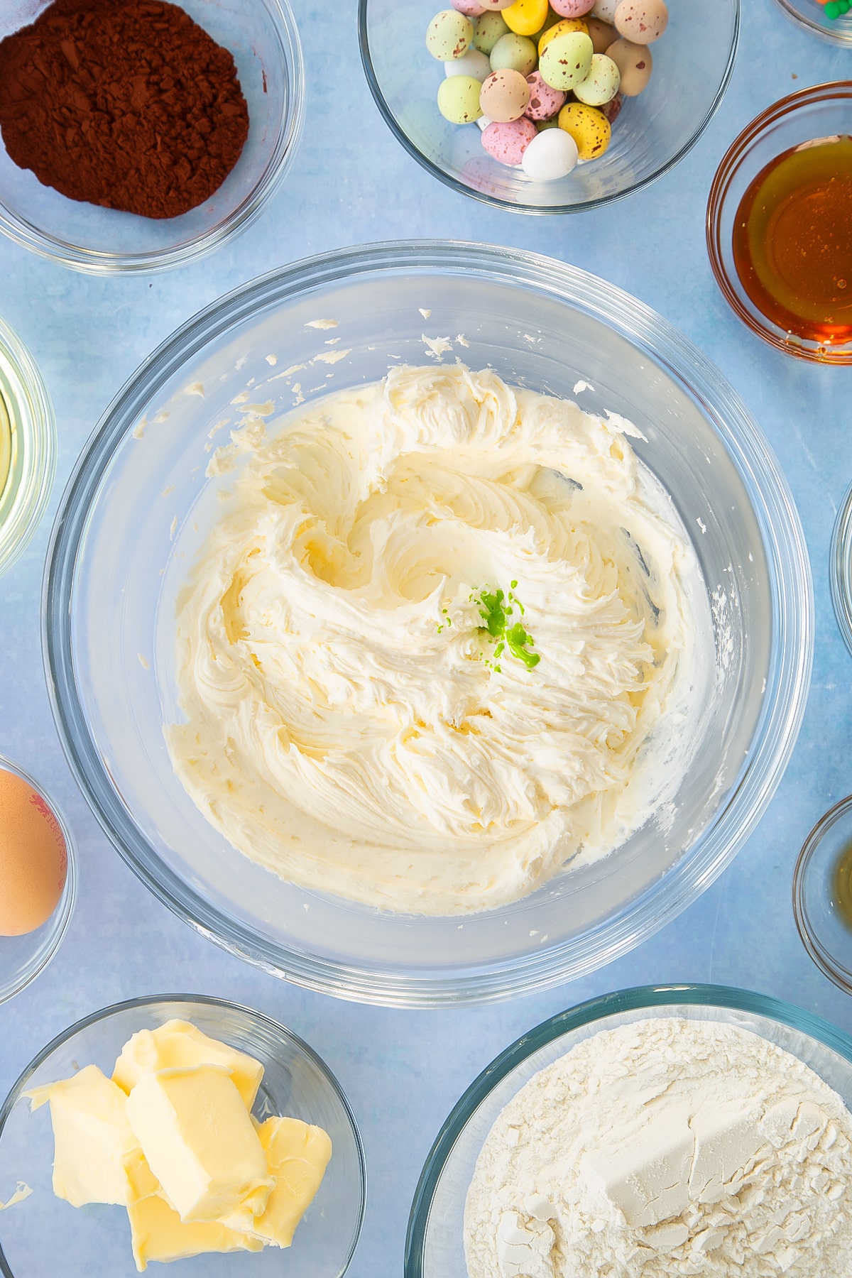 Icing ingredients in a mixing bowl with some green food colouring.