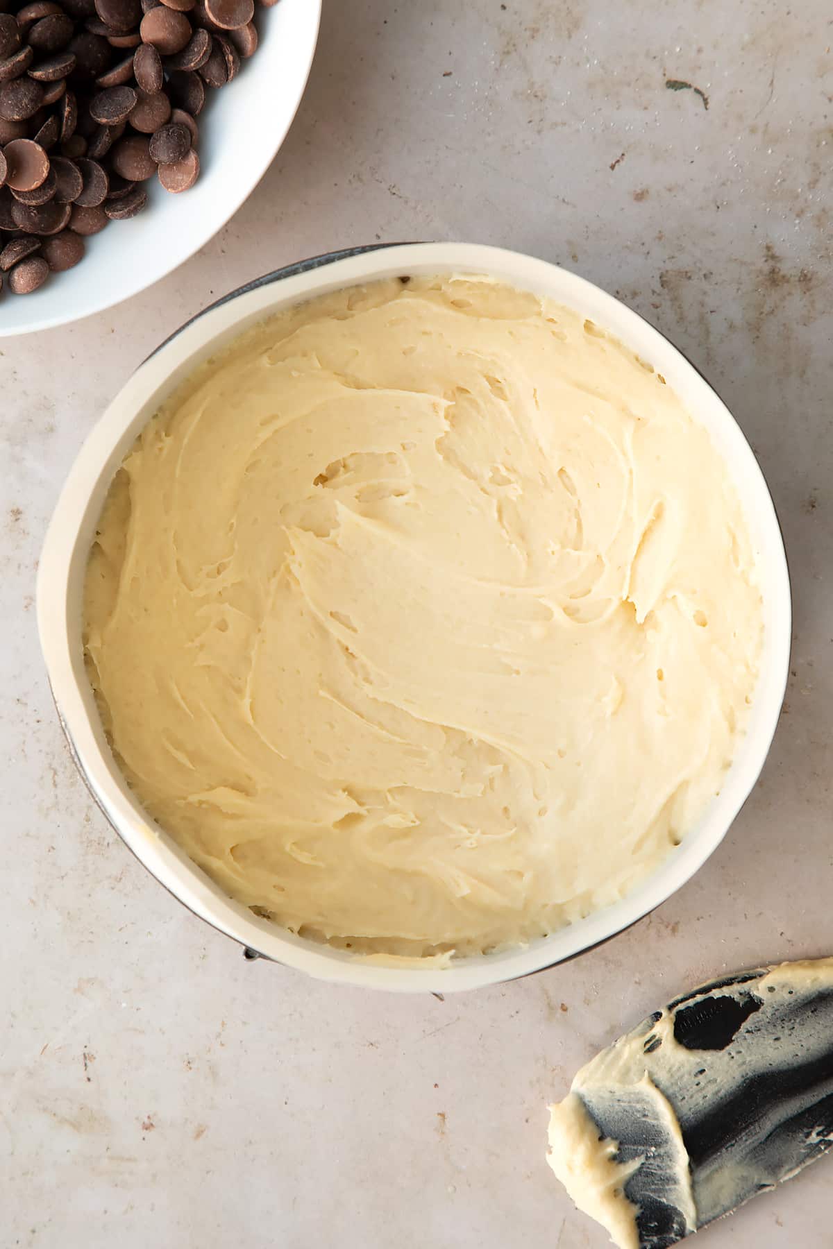 cake batter in a lined round cake tin surrounded by ingredients.