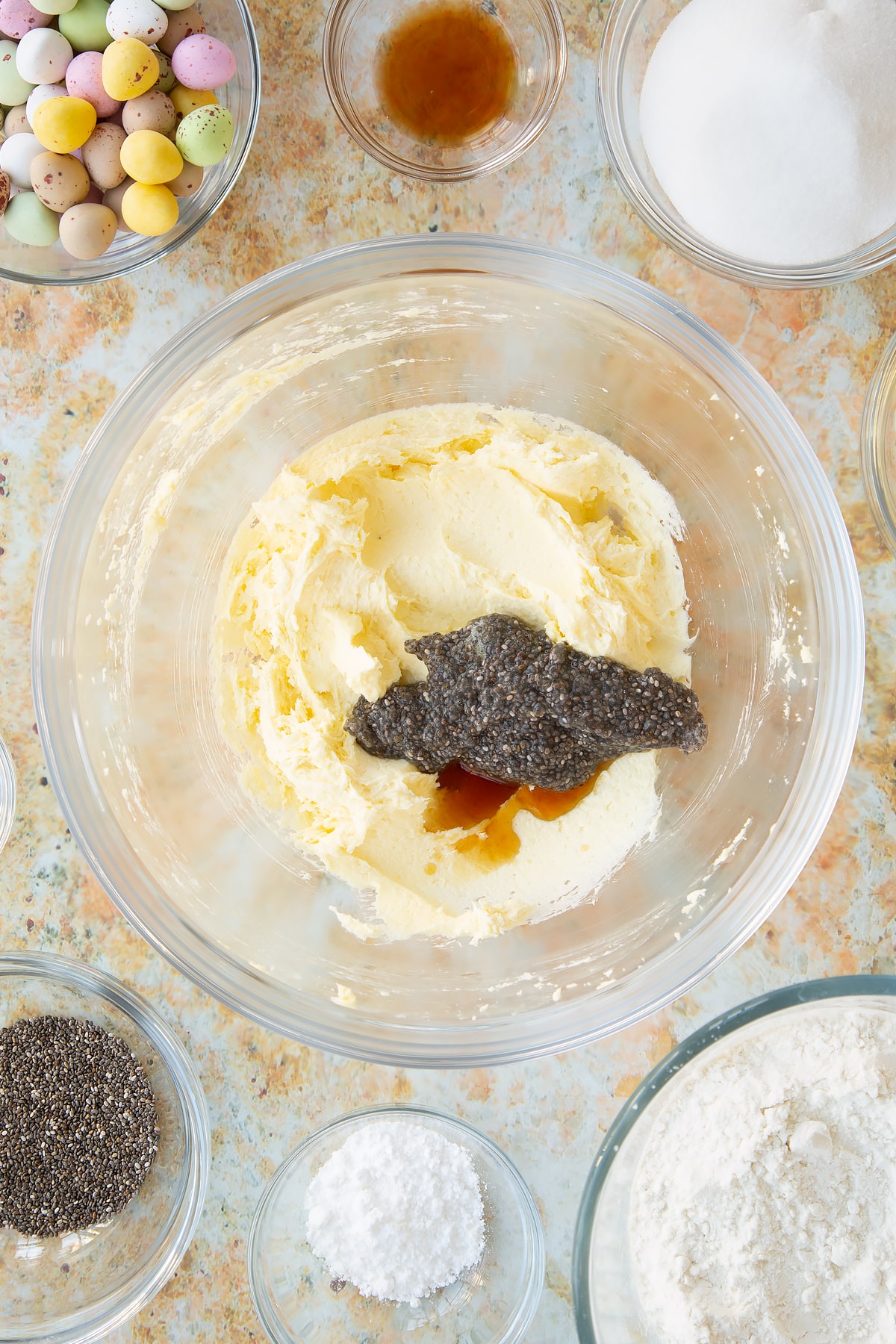 Ovehread shot of chia seeds and vanilla being added to the mixing bowl.