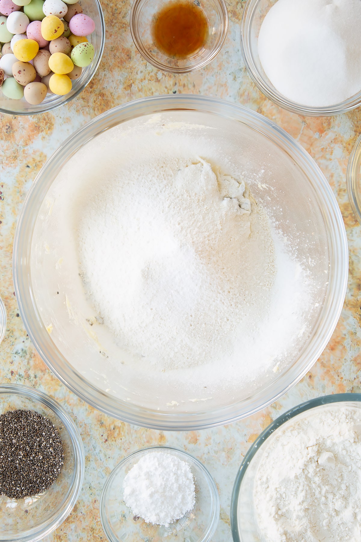 Sifting in the gluten free flour, baking powder, salt and bicarbonate of soda into the mixing bowl of ingredients.