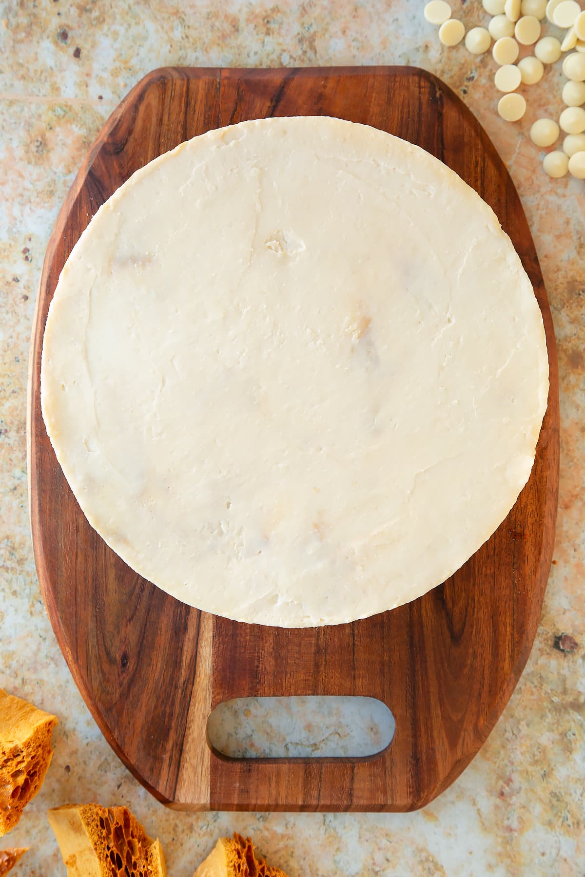 white chocolate honeycomb cheesecake on a wooden chopping board.