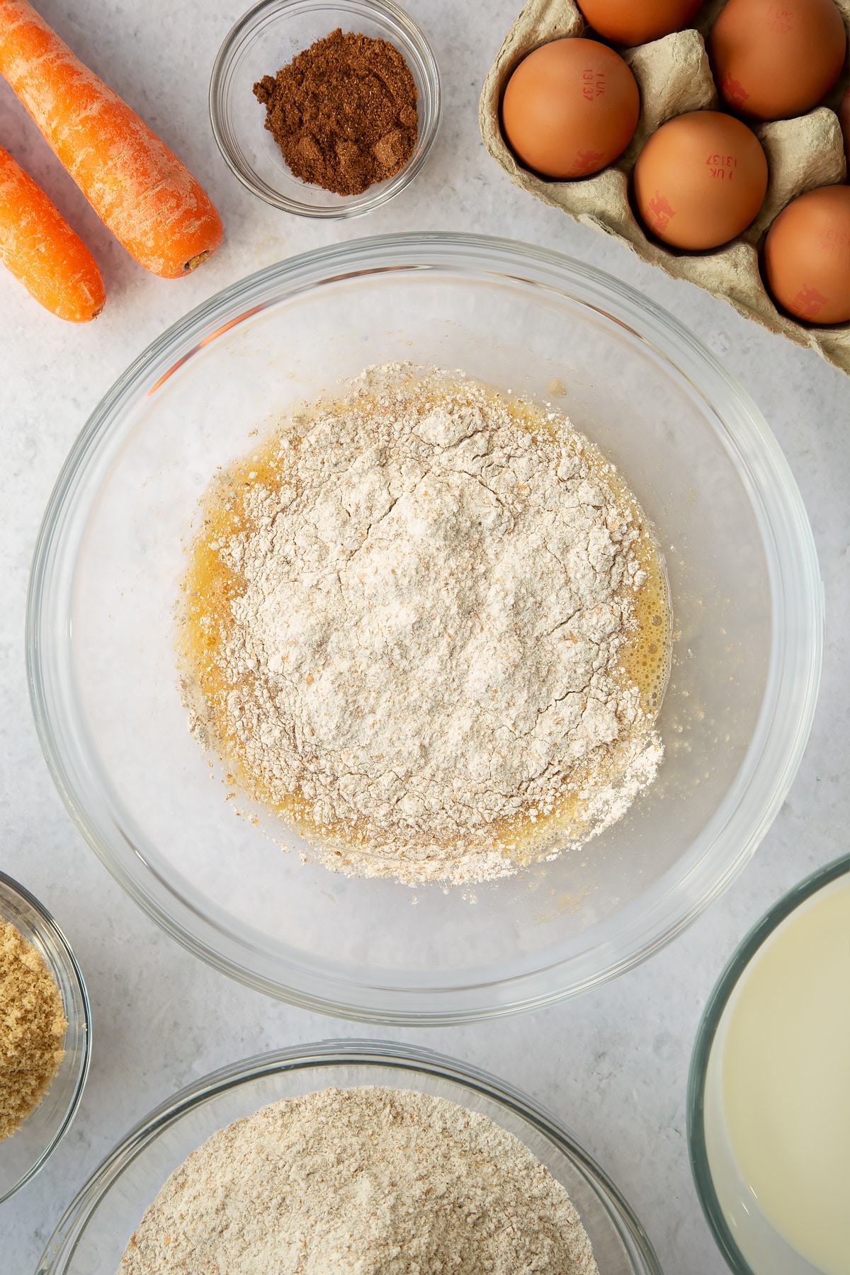 whisked eggs and sugar mixture in a large clear bowl topped with sieved flour.