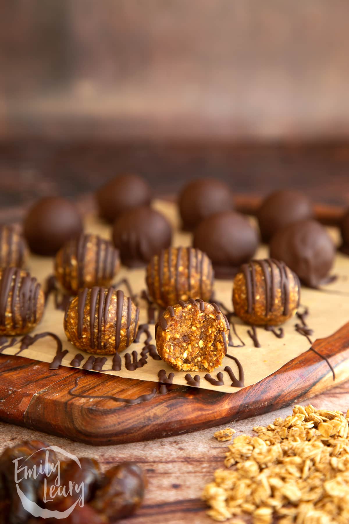 a half eaten Date energy ball on a wooden chopping board full of Date energy balls.