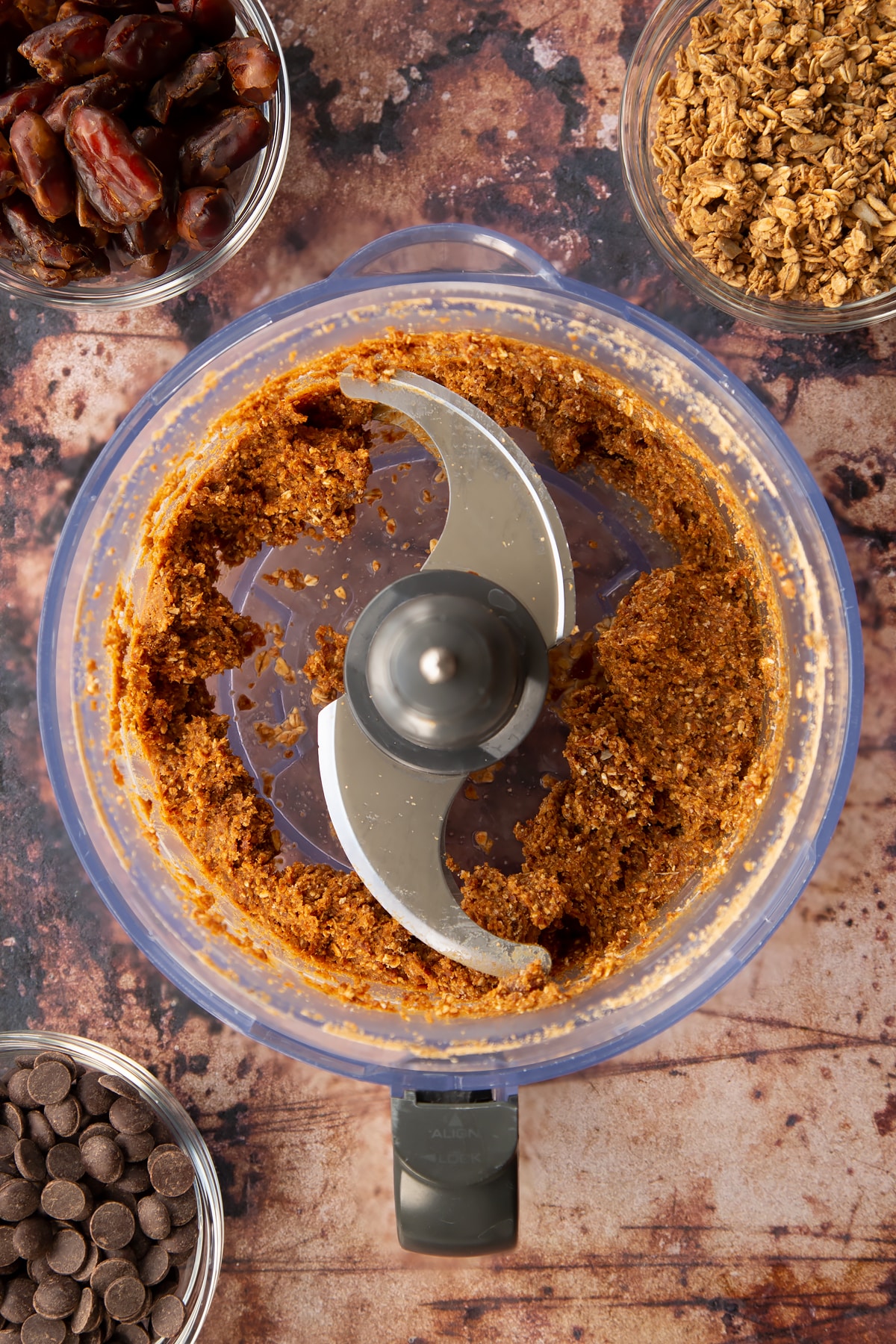 blitzed dates and granola in a food procesor surrounded by ingredients.