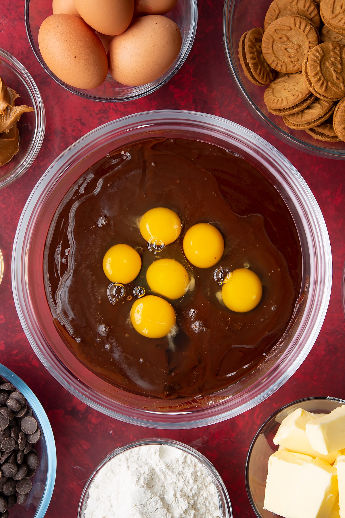 mixed sugar and melted chocolate mix in a large clear bowl topped with 6 eggs.