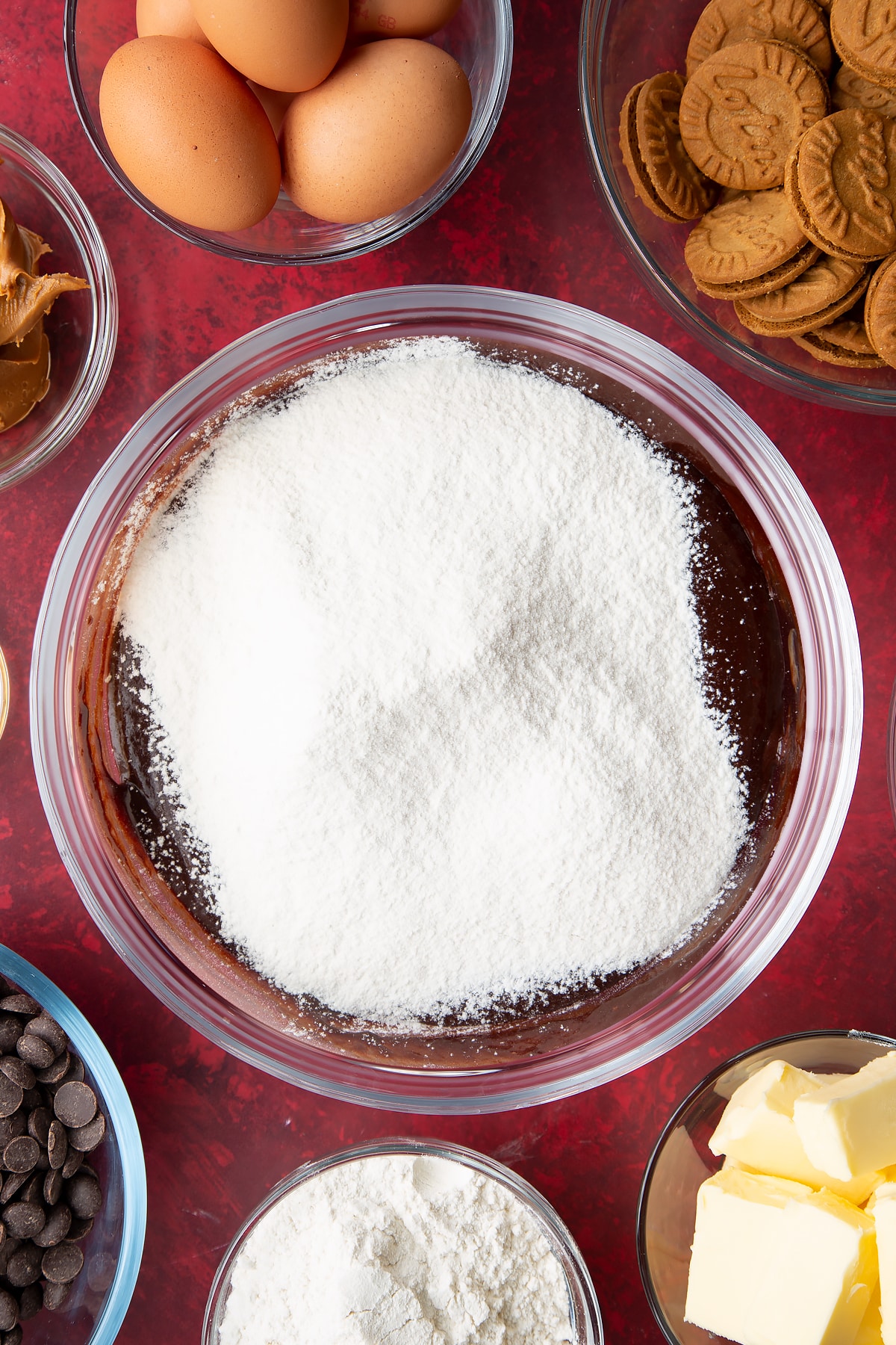 melted chocolate sugar mix in a large clear bowl topped with sieved flour.