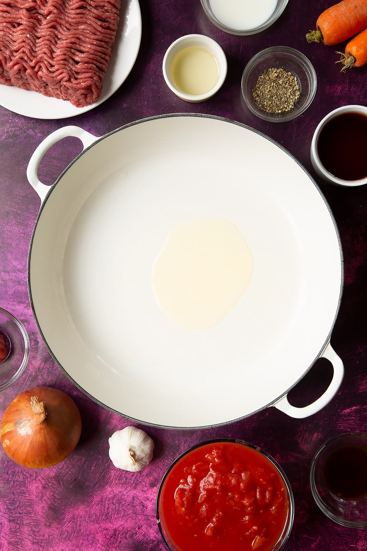 oil in a large white frying pan surrounded by ingredients.
