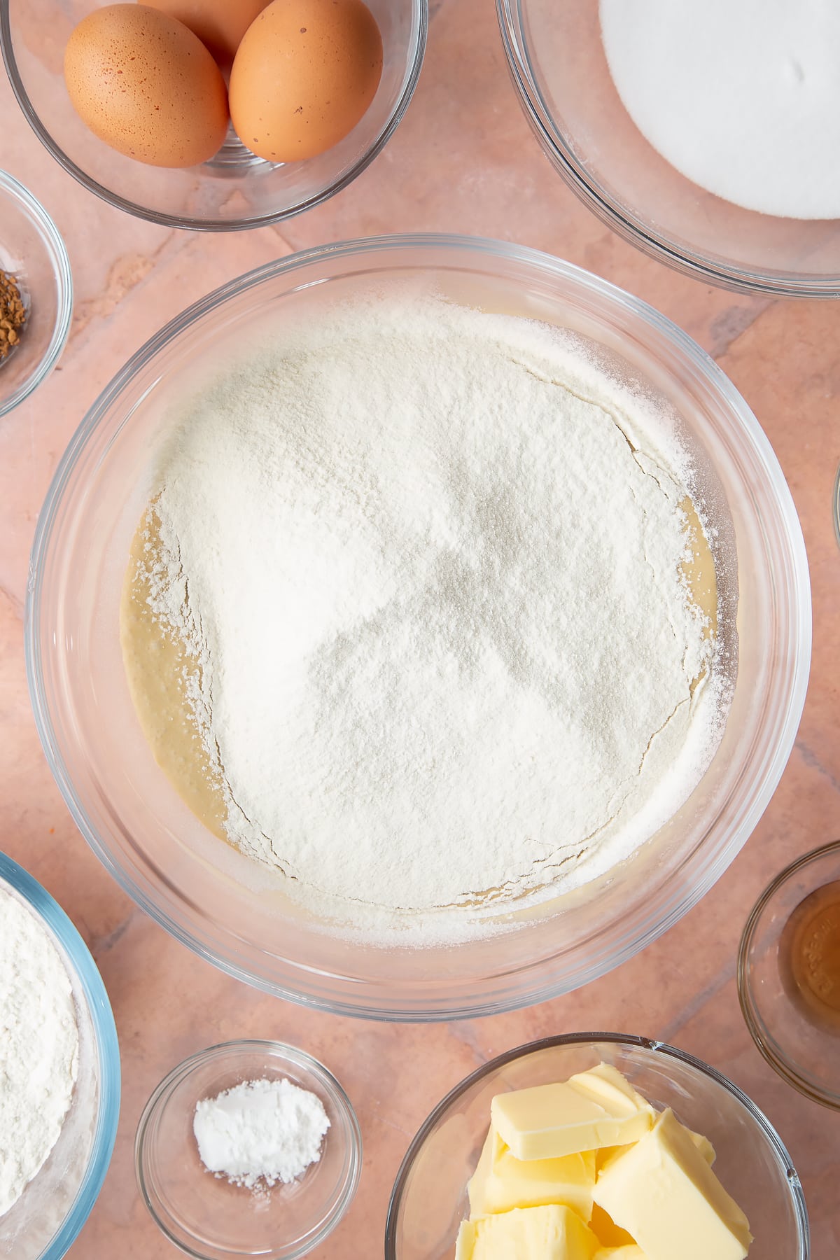 coffee cake mix topped with sieved flour in a large clear bowl.