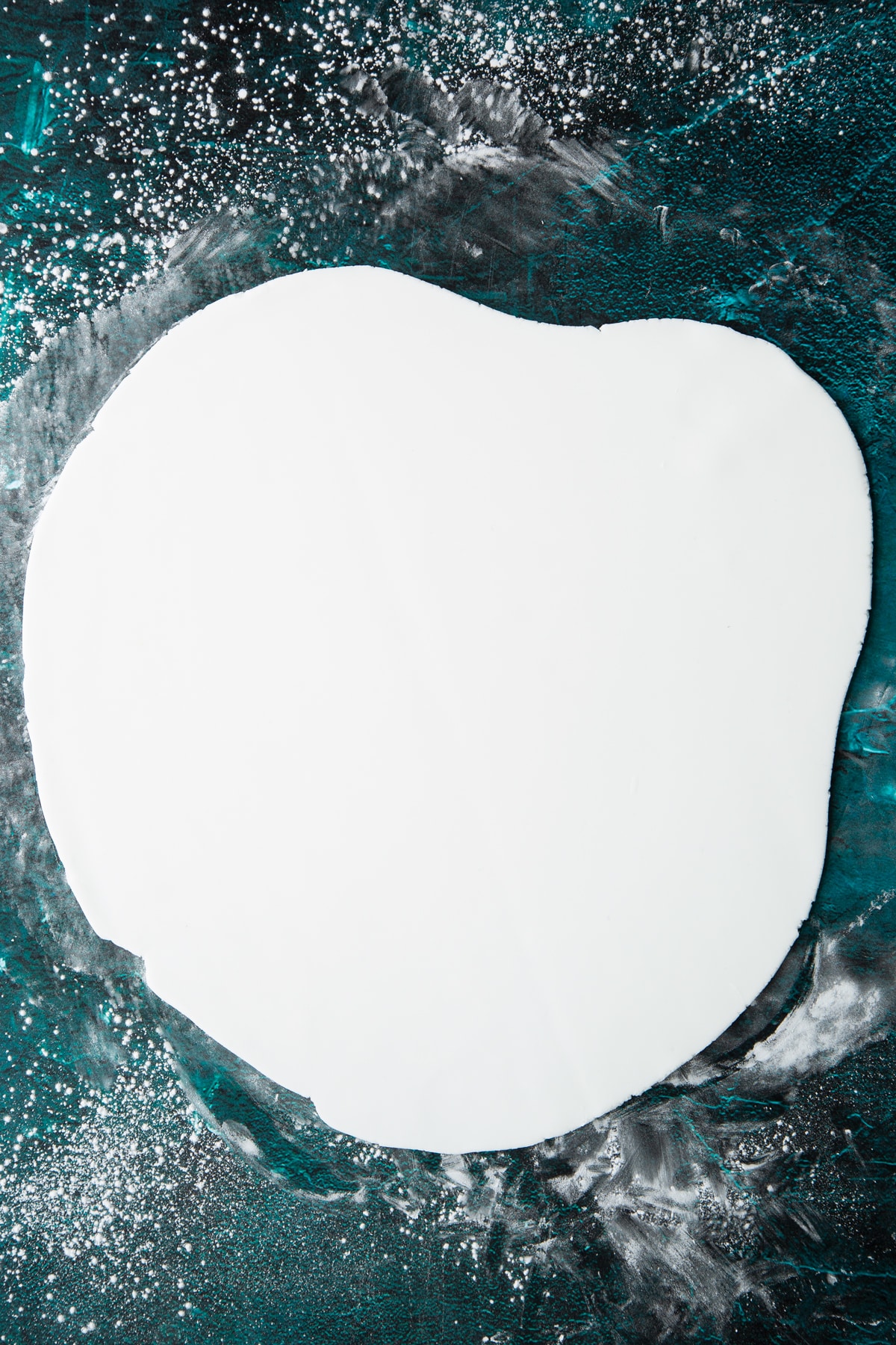 white royal icing rolled out thin on a green marble background.