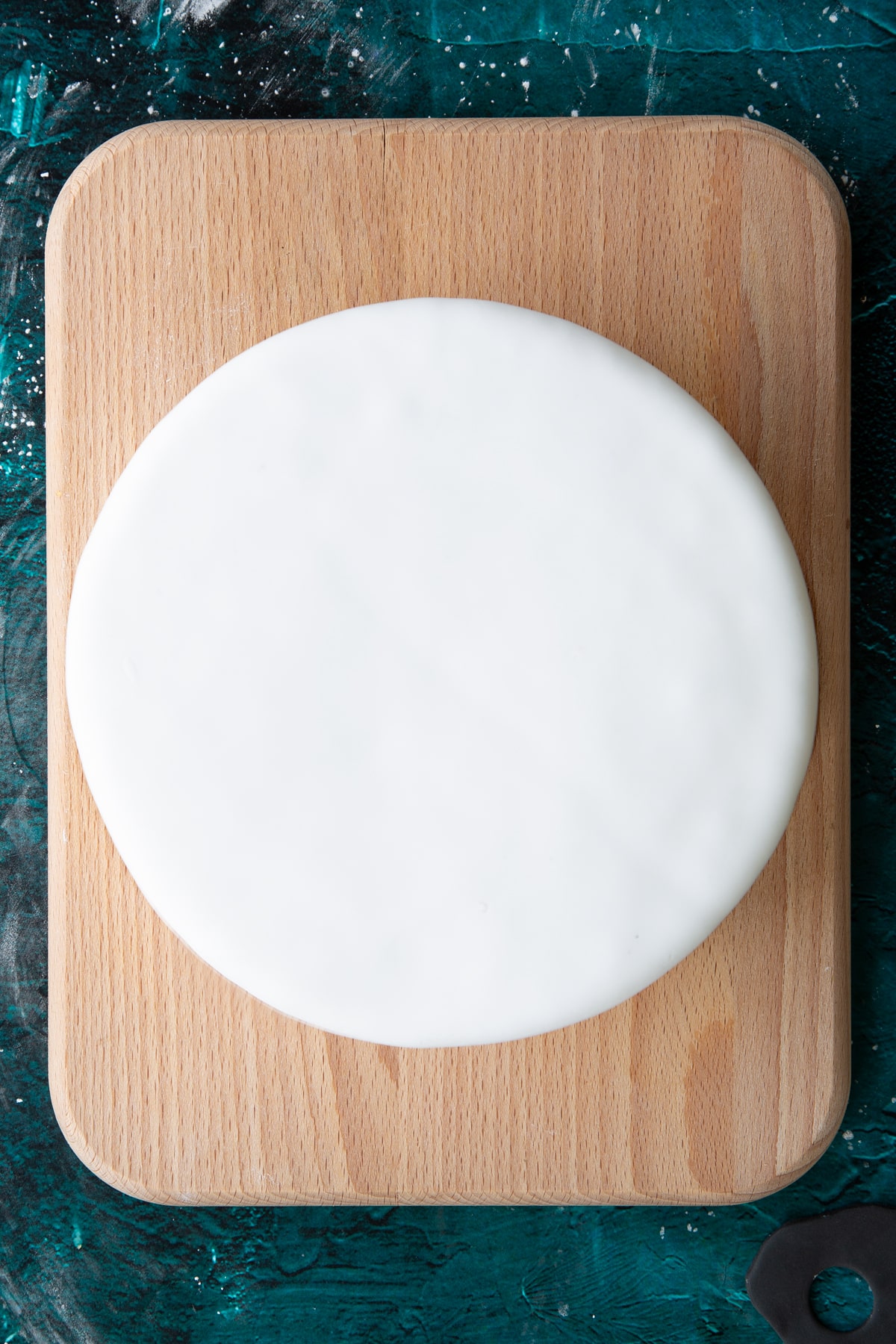 round cake covered with smooth white royal icing on a wooden board.