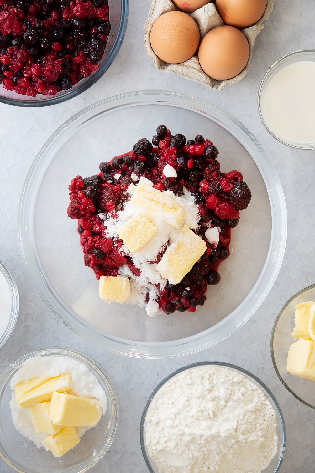 frozen fruit, butter and sugar in a large clear bowl.