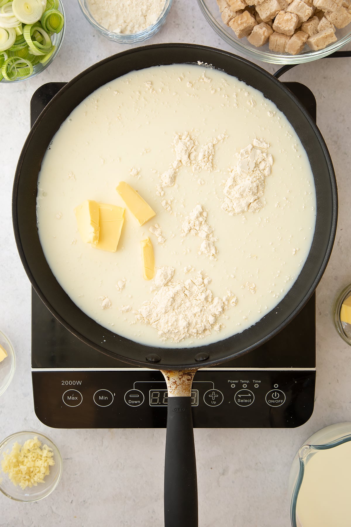 milk butter and flour in a large frying pan on an induction hob.