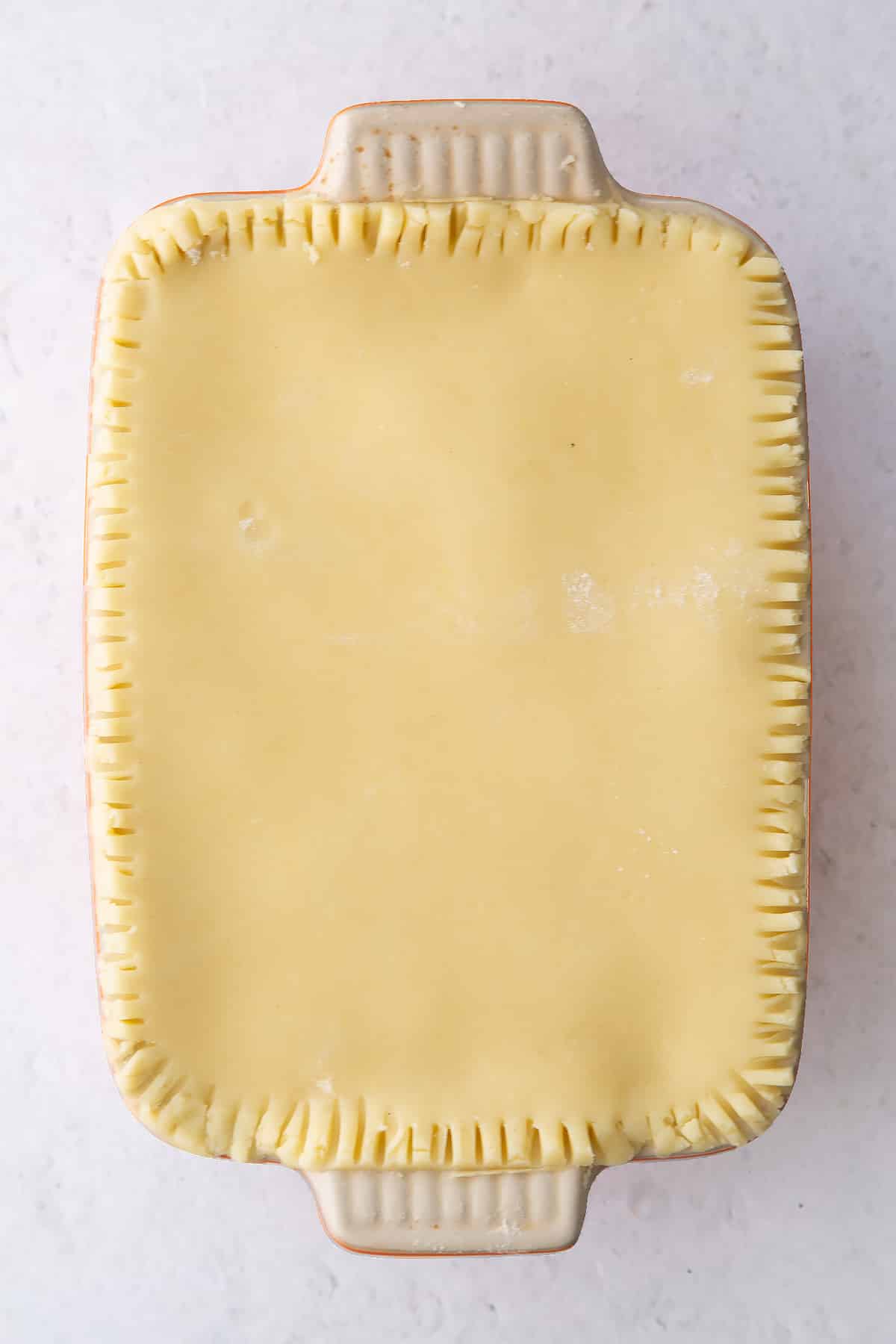 rolled out gluten free pastry pressed to a small roasting dish with ffork style edging.