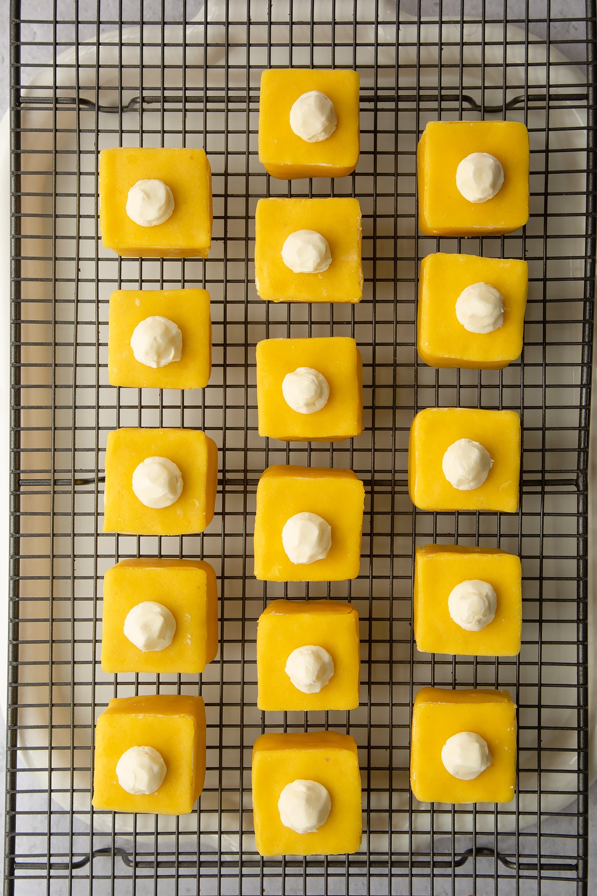 Placing the fondant fancies on a wire rack to cool.