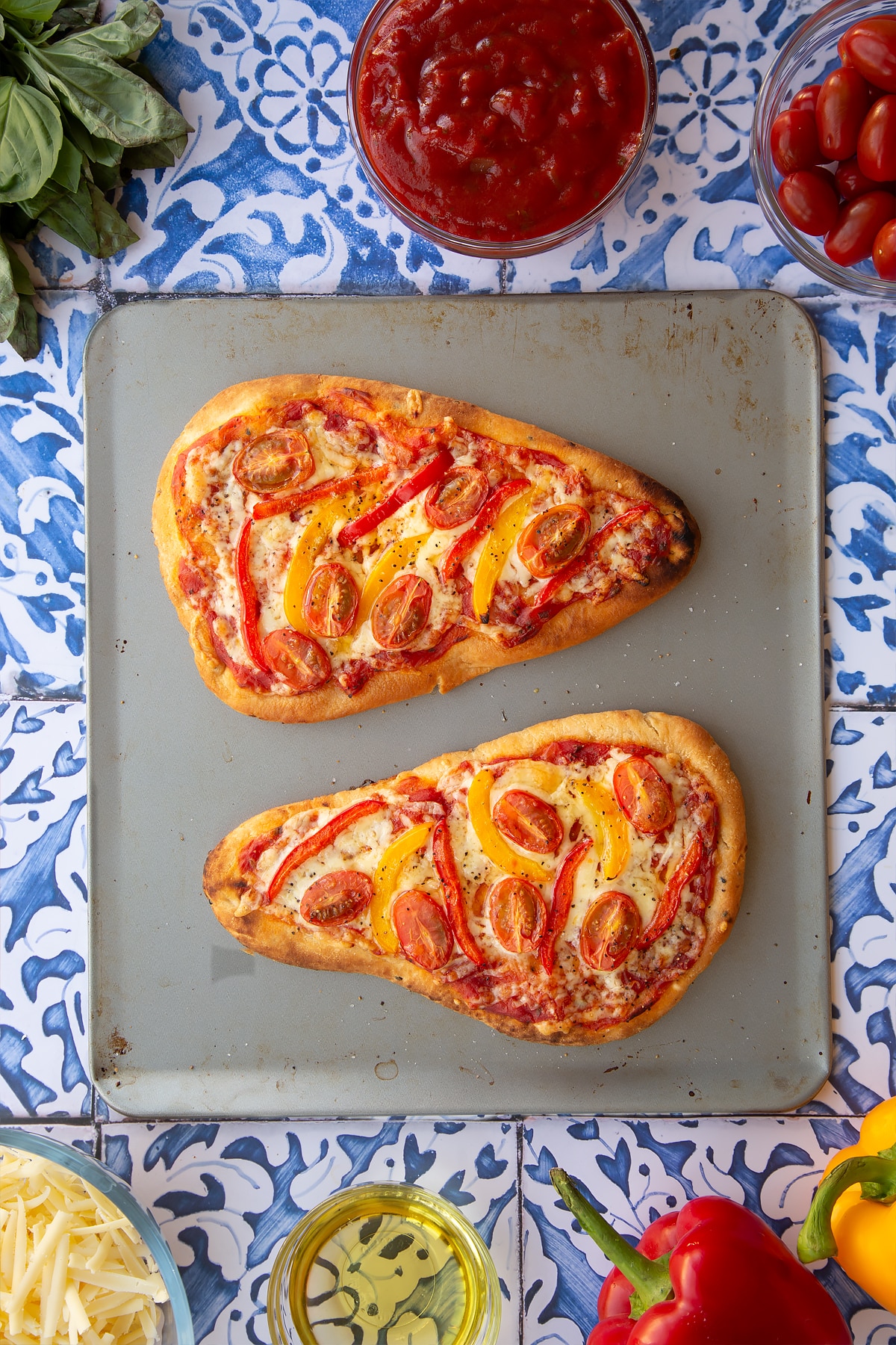 Two cooked naan bread pizzas ontop of a square baking tray.